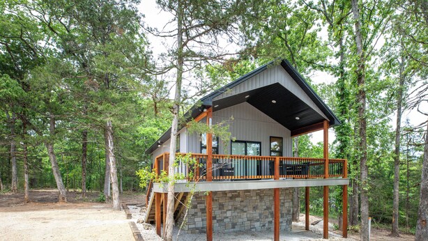 Une cabane avec des fondations en pierre, une terrasse en bois et un porche abrité.