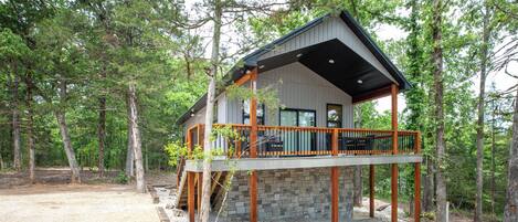 A cabin with a stone foundation, wooden deck, and a covered porch.
