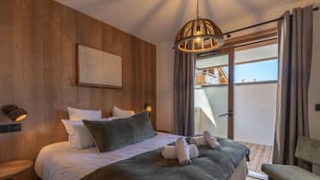 Ein Schlafzimmer mit hölzernem Kopfteil, einem Bett mit weißer und grüner Bettwäsche, einer Pendelleuchte und Blick auf einen Balkon.