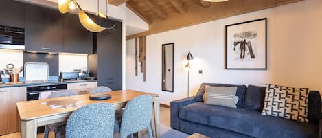 A modern kitchen with dark cabinetry, a dining table with chairs, and a wooden ceiling.