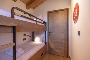 A bunk bed room with a wooden door and a wall-mounted sign. - TERRESENS - La Perle d'Alba (Huez)