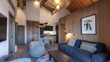 A modern living room with a wooden ceiling, a sofa, a coffee table, and a dining area with chairs.