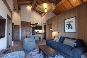 A modern living room with a wooden ceiling, a sofa, a coffee table, and a dining area with chairs. - TERRESENS - La Perle d'Alba (Huez)