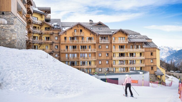 A multi-story hotel with balconies and ski slopes in the background. - TERRESENS - La Perle d'Alba (Huez)