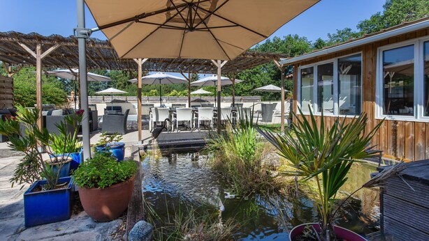A patio area with outdoor seating, a small water feature, and potted plants.