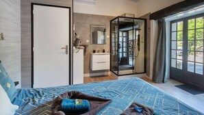 A bedroom with a bed, a bathroom with a mirror, and a door leading to a balcony.