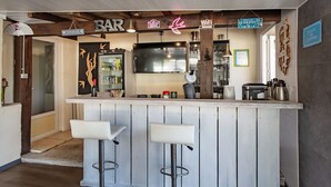 A bar area with two stools, a TV, and a sign that says 'Place de l'Avro'.