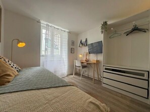 Ein Schlafzimmer mit Bett, Schreibtisch, Stuhl, Fernseher und Kleiderschrank.