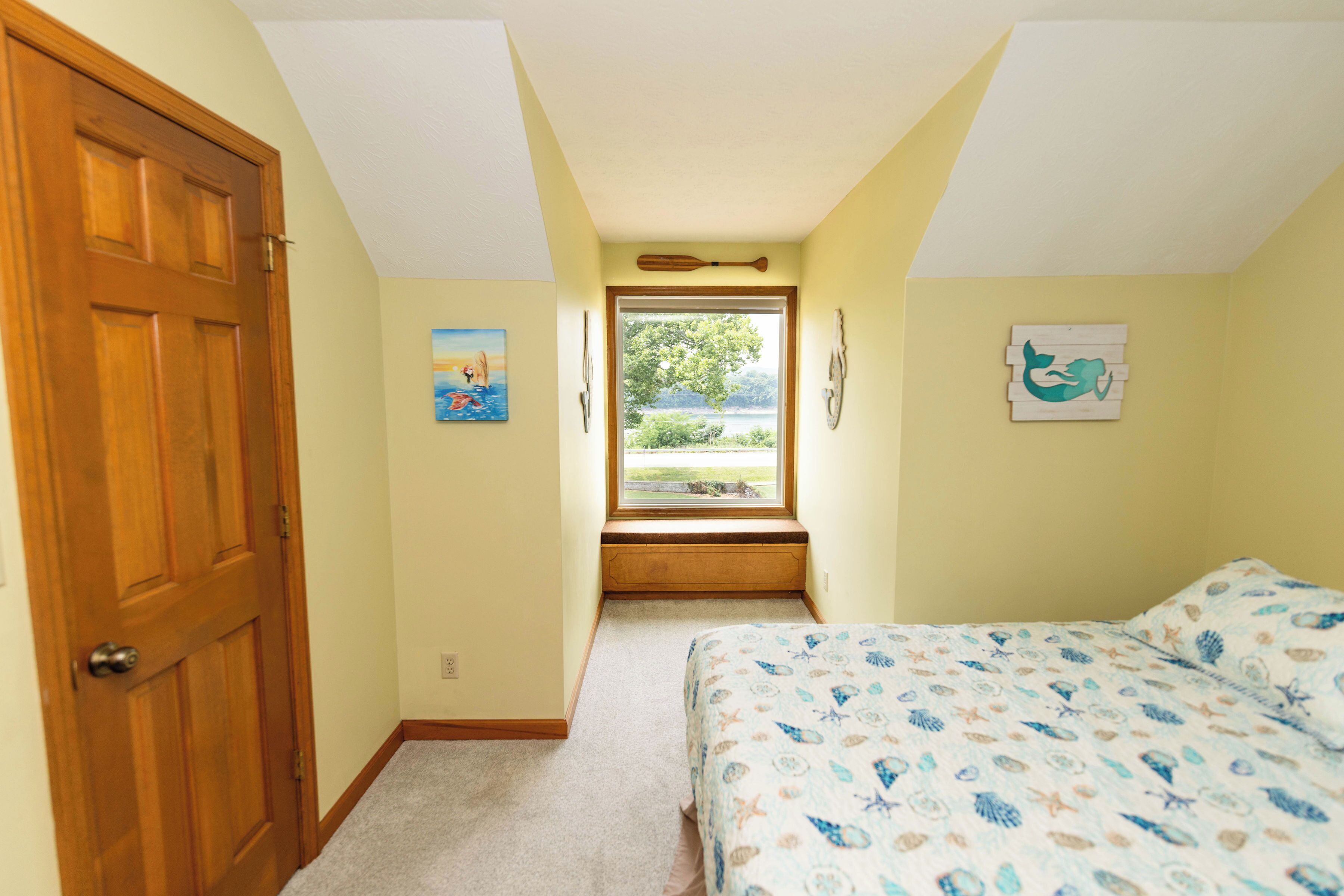 Une chambre à coucher avec un lit, une fenêtre, une porte et des œuvres d’art mural.