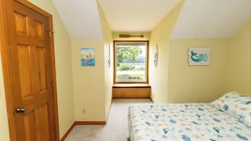 Une chambre à coucher avec un lit, une fenêtre, une porte et des œuvres d’art mural.