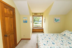 A bedroom with a bed, a window, a door, and wall art. - Louie's Front Porch (Burnside)
