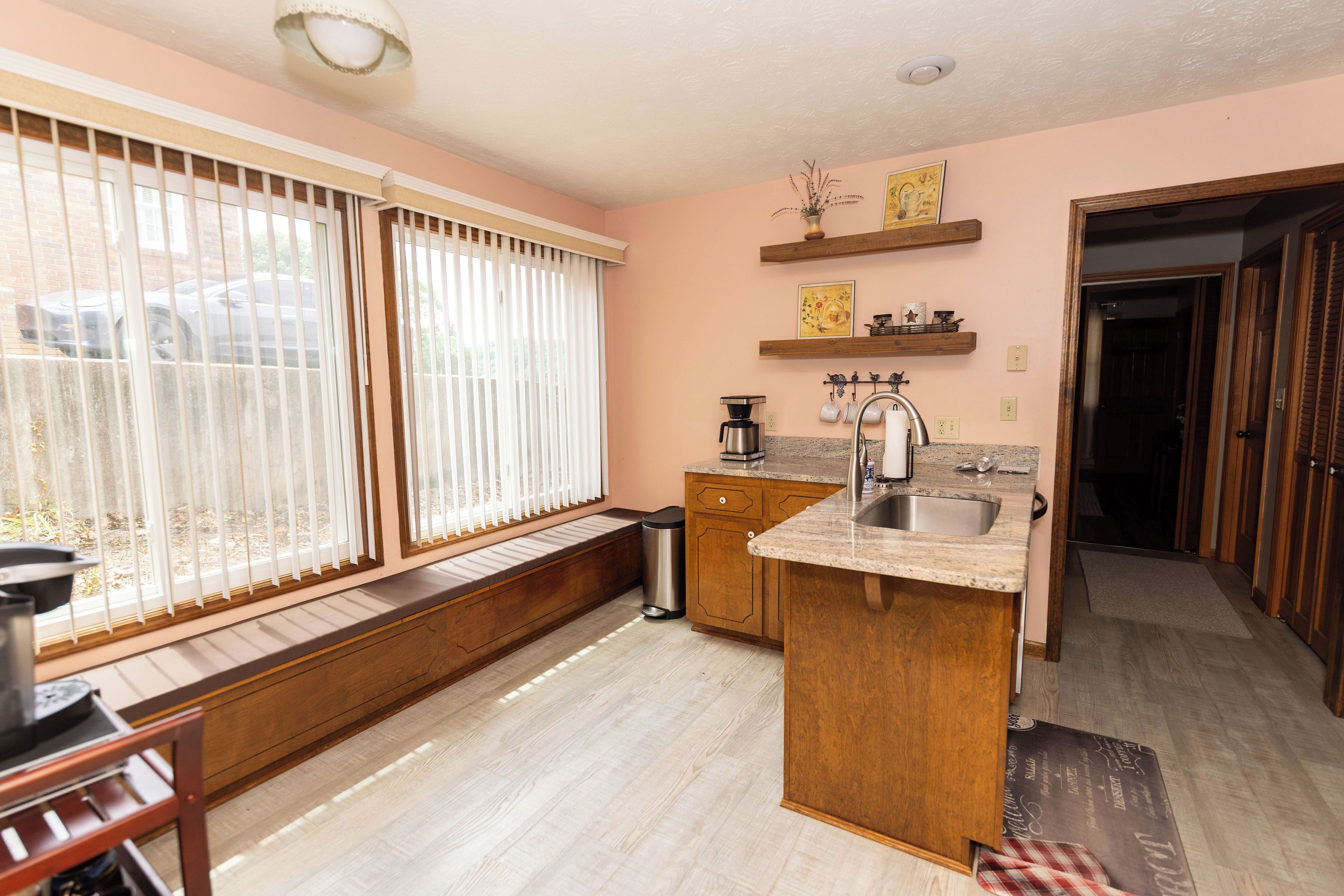 A kitchen with wooden cabinets, a countertop sink, and a window with blinds.