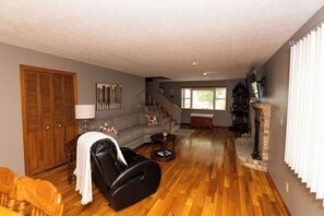 A living room with a sofa, a massage chair, a fireplace, and a staircase leading to another level. - Louie's Front Porch (Burnside)