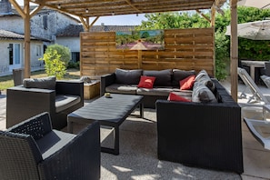 Un patio al aire libre con mobiliario de mimbre, una mesa y un cuadro en la pared.