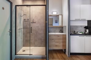 A modern bathroom with a glass-enclosed shower, a wooden vanity with a mirror, and a sink.