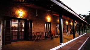 A brick building with a covered patio, outdoor seating, and a hammock. - Quinta dos Cambaras Ecopousada (Itaí)
