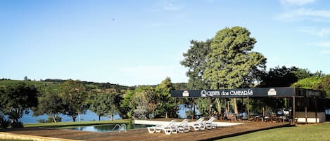 Una piscina al aire libre, sombrillas, sillones reclinables de piscina