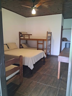 A room with a bunk bed, a desk, and a ceiling fan.