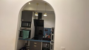 Une cuisine compacte équipée d’un four à micro-ondes, d’un four traditionnel et d’un évier, le tout sous un plafond en arc surmonté de luminaires suspendus.
