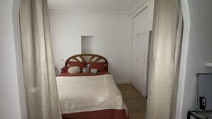 Une petite pièce comprenant un lit, une armoire et une porte.