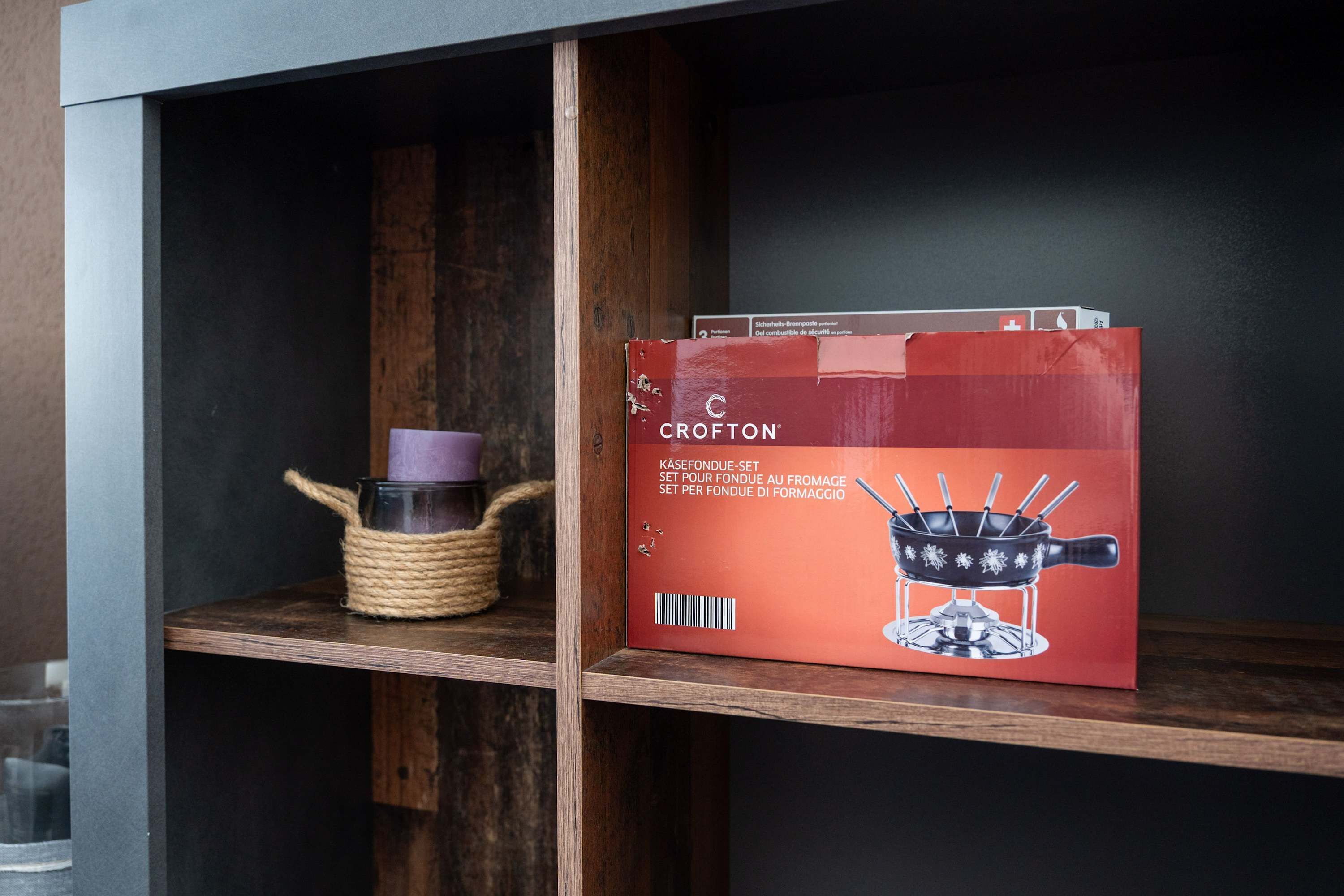 A shelf with a red box labeled 'Crofton' and a woven basket with a purple object.