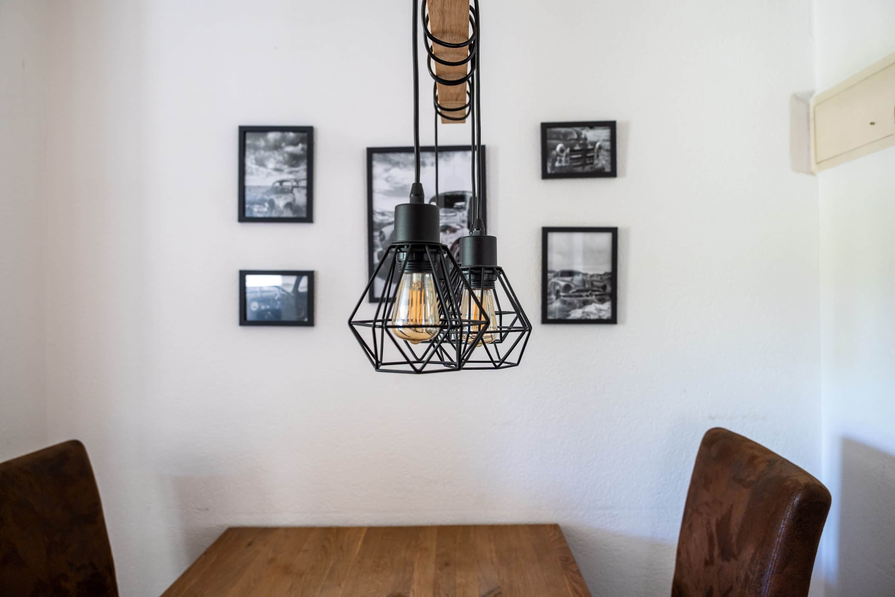 Un comedor con una mesa y sillas de madera, una lámpara colgante y cuadros en la pared.