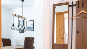 Un'area pranzo con tavolo e sedie in legno, una lampada a sospensione e un armadio in legno con specchio.