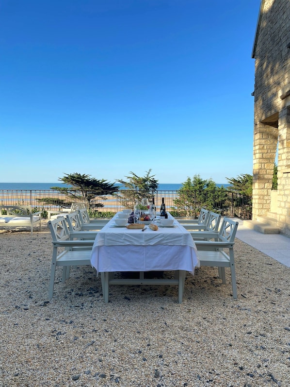 An outdoor dining area with a table set for two, overlooking a beach.