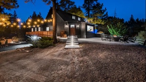 Een modern huis met een houten terras, een vuurkorf en buitenmeubilair.