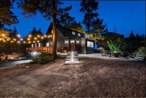 Ein modernes Haus mit einer Holzterrasse, einem Feuerkorb und Sitzgelegenheiten im Freien.