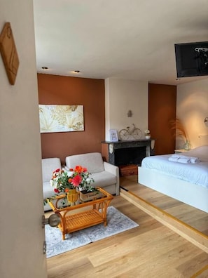 A living room with a sofa, a coffee table with flowers, a fireplace, and a bed. - Clemanbruges (Bruges)