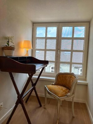 A room with a window, a lamp, a chair, and a stand. - Clemanbruges (Bruges)