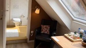 A small, cozy room with a skylight, a chair, a table with various items, and a view of the outside. - Clemanbruges (Bruges)