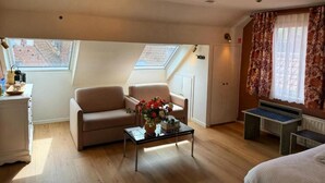 A room with a sofa, a coffee table with flowers, a desk, and a bed. - Clemanbruges (Bruges)