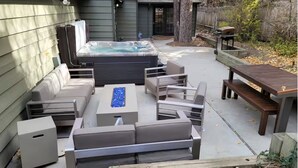 Patio esterno con idromassaggio, divani e tavolo in legno.