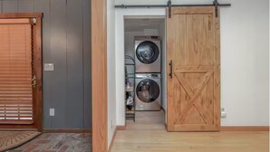 Una lavanderia con due lavatrici affiancate e una porta scorrevole in legno.