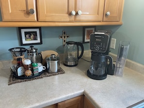 A kitchen counter with a coffee maker, a kettle, a coffee press, and various kitchen utensils. - Stylish Family Home: Walk to Downtown Commerce 10 guests: 5BR/4BA (Commerce)