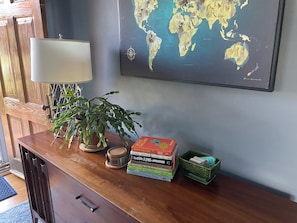 A wooden desk with a globe map, a lamp, a potted plant, and a stack of books. - Stylish Family Home: Walk to Downtown Commerce 10 guests: 5BR/4BA (Commerce)
