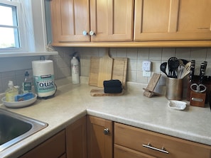 A kitchen with wooden cabinets, a countertop, a cutting board, a knife block, and a dish rack. - Stylish Family Home: Walk to Downtown Commerce 10 guests: 5BR/4BA (Commerce)