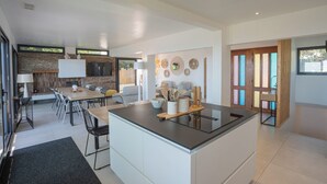 Una cocina moderna con una isla central, comedor con sillas y una pared de piedra.