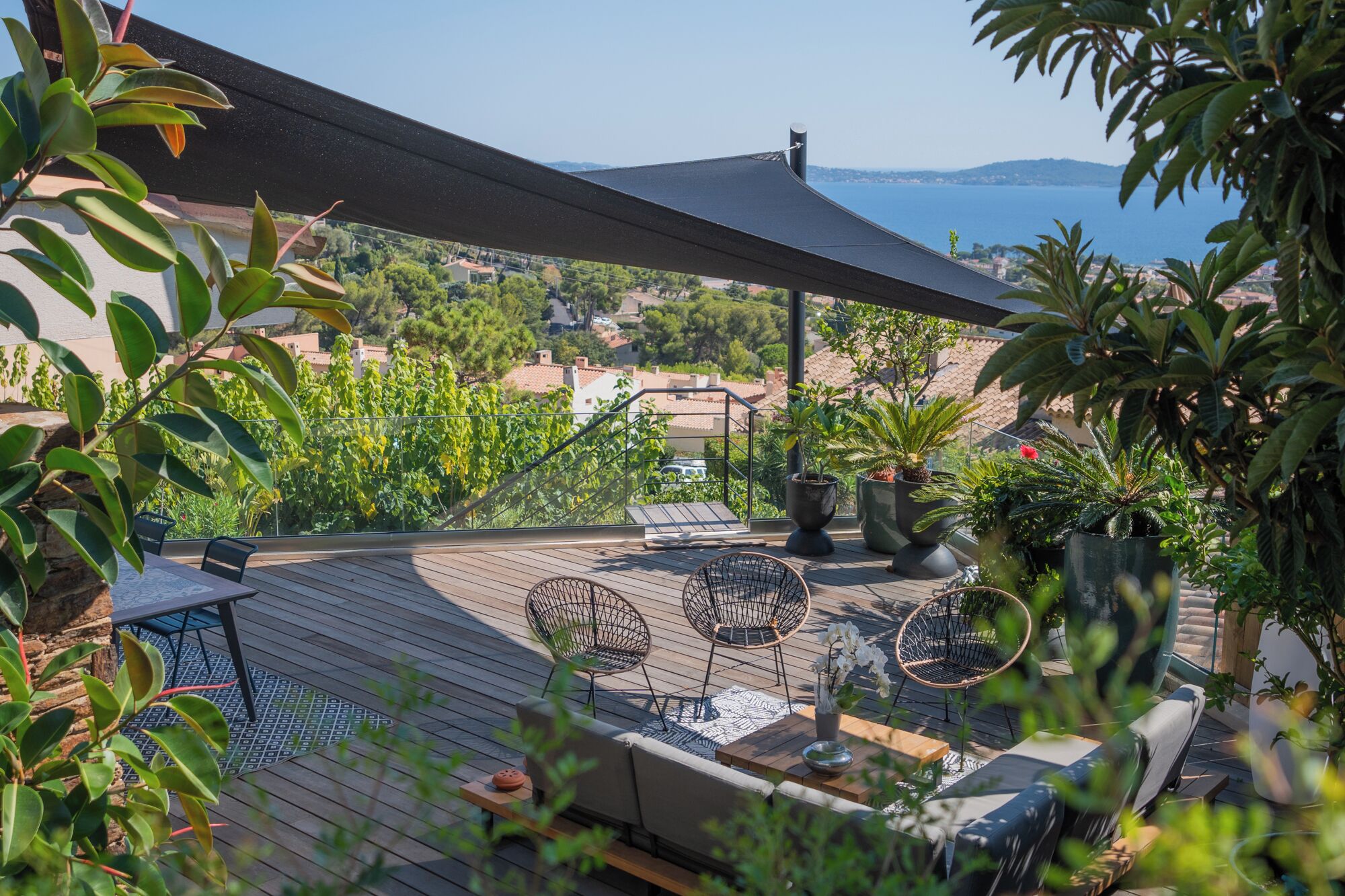 A rooftop terrace with wooden flooring, outdoor seating, and potted plants.