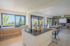 Una cocina moderna con una isla central, ventanas amplias y una chimenea de piedra.
