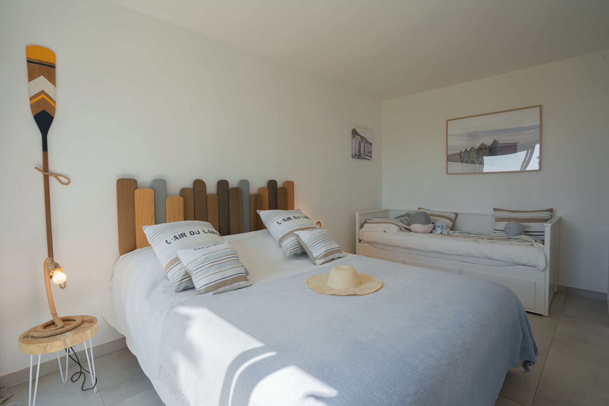 A bedroom with a bed, two bedside tables, a cat tree, a wall-mounted lamp, and a framed picture.