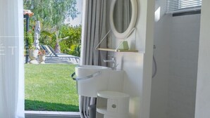 A bedroom with a bed, a bathroom with a sink, a mirror, and a view of a garden. - Villa in Carqueiranne. Beautiful sea views, 5 bedrooms, heated swimming pool. (Carqueiranne)