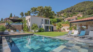 A modern pool area with a checkered tile pattern, surrounded by outdoor seating and a well-maintained lawn. - Villa in Carqueiranne. Beautiful sea views, 5 bedrooms, heated swimming pool. (Carqueiranne)
