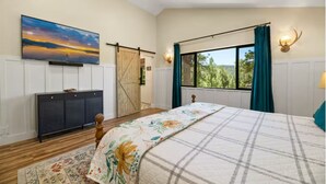 Ein Schlafzimmer mit Bett, Vorhängen am Fenster, Heizkörper, Kleiderschrank und einem Bild an der Wand.