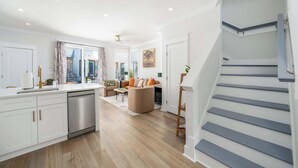 Une cuisine moderne équipée d’un lave-vaisselle, un coin repas avec une table et des chaises, et un escalier.