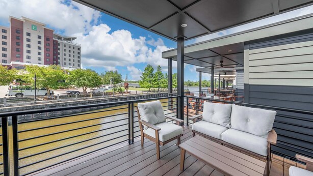 Un balcon donnant sur une rivière, un canapé blanc et une chaise en bois.