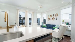 A modern kitchen with a large island, white cabinetry, and a built-in dishwasher.