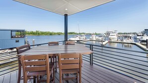 A covered outdoor area with a table and chairs, overlooking a marina with boats.